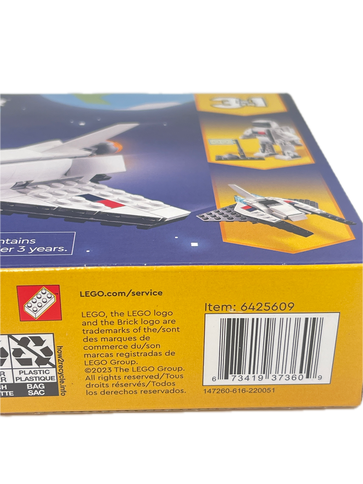 Close-up of the back of a LEGO box showing a barcode, product information text, recycling logo, and small LEGO branding on a yellow and blue package.