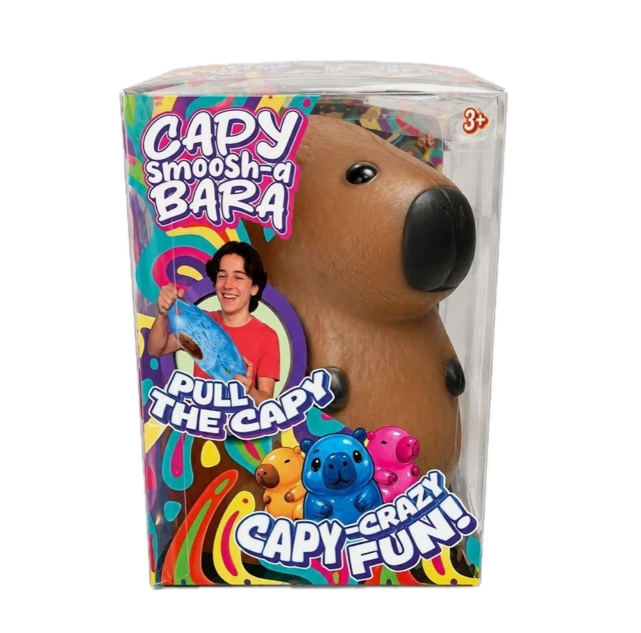 A packaged Capy Smoosh-a-Bara toy in clear plastic box packaging, showing a brown capybara-shaped squishy toy with a black nose and eyes. The box has colorful retro graphics with text including 'Capy Smoosh-a Bara', 'Pull the Capy', and 'Crazy Fun!'.
