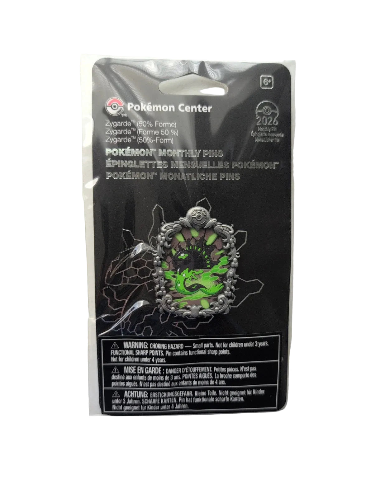 A packaged Pokémon Center enamel pin on a black backing card, photographed against a white wall. The pin features a green and black spider design with silver-toned metal details.