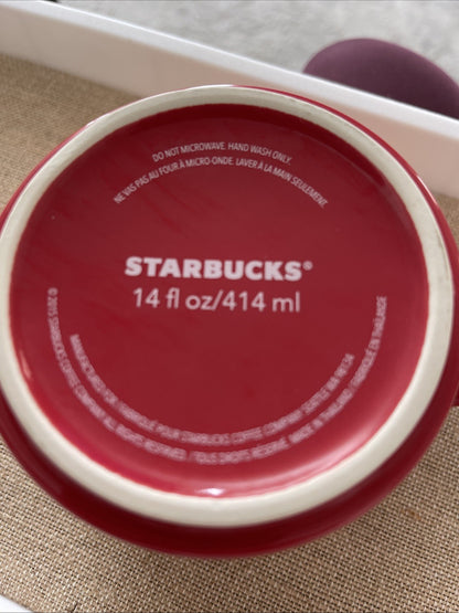Red lid of a Starbucks cup with white text on a textured surface