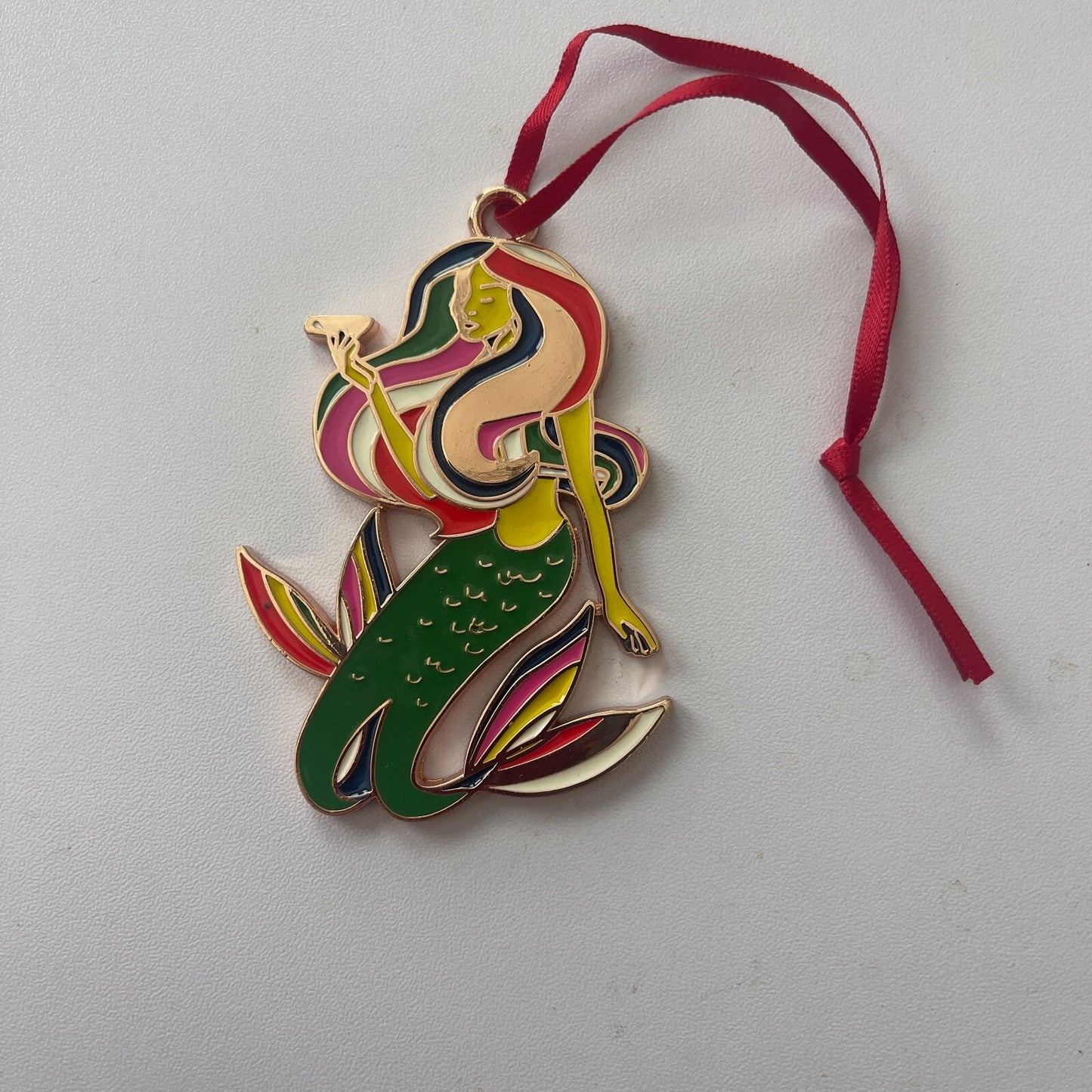 Colorful mermaid ornament with a red ribbon on a light gray background
