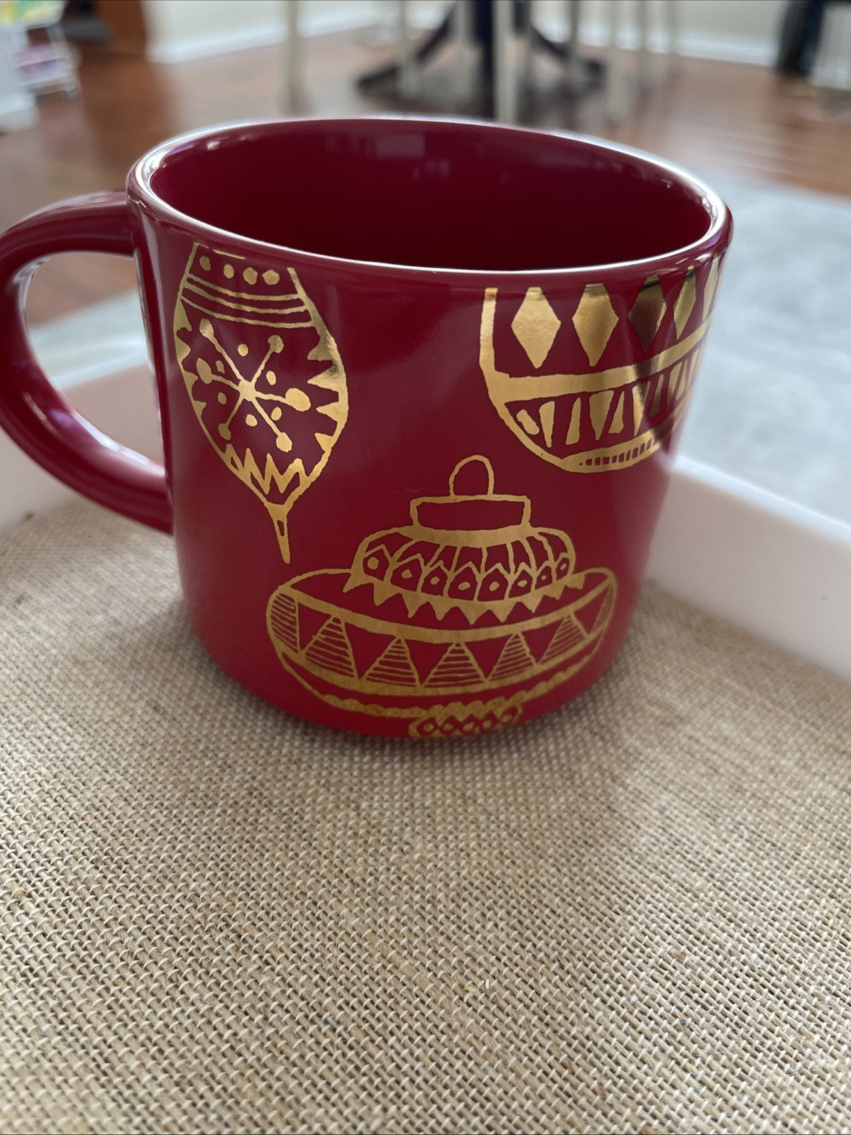 Red mug with gold patterns on a textured surface