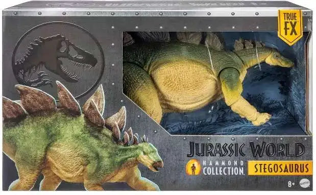 Jurassic World Stegosaurus toy in its original window box packaging by Hammond Collection. The packaging features a dark gray metallic design with illustrations of the green and tan Stegosaurus, a black T-Rex logo, and a yellow 'True FX' badge.