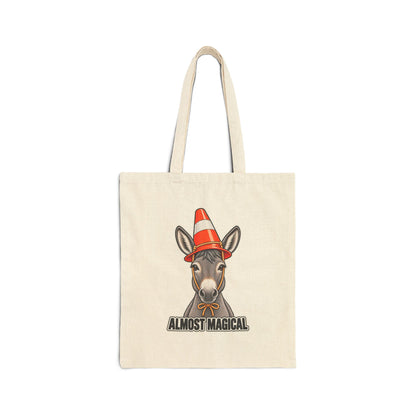 An off-white canvas tote bag with a printed graphic of a donkey wearing an orange and white traffic cone hat, with the text 'ALMOST MAGICAL' below, shown against a plain white background.