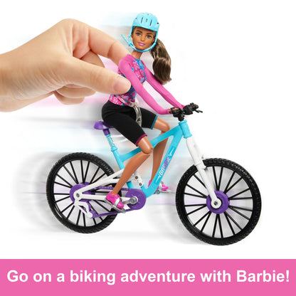 Barbie doll riding a bicycle with a hand holding it, on a white background.