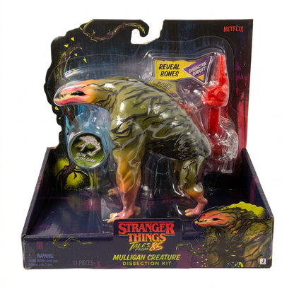 Stranger Things Mulligan Creature Dissection Set toy in its original packaging, featuring a green and yellow creature figure with a red tool and blue accessory, on a white background.