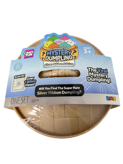 A packaged toy product labeled 'The Original Viral Mystery Dumpling' by Crazy Fun and RKS, shown in a clear plastic-wrapped round container with a printed cardboard hanger card. The visible product inside appears to be a beige/tan dumpling-shaped item, and the packaging prominently features blue, yellow, orange, and multicolor graphics.