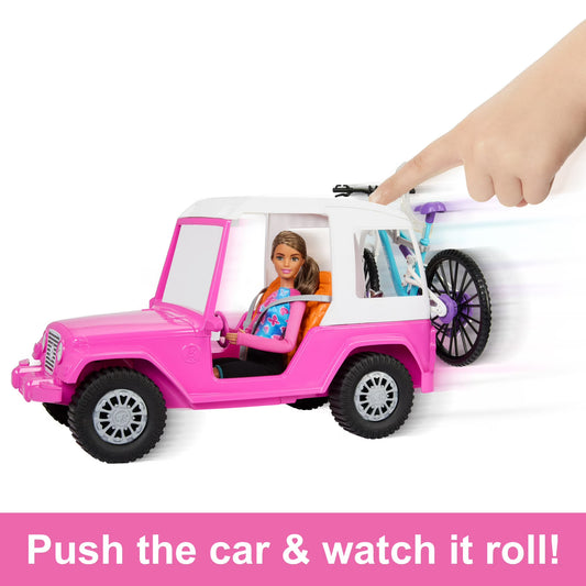 A pink and white toy jeep with a doll inside, shown on a white background with a human hand pushing the back wheel. A text banner at the bottom reads 'Push the car & watch it roll!'.