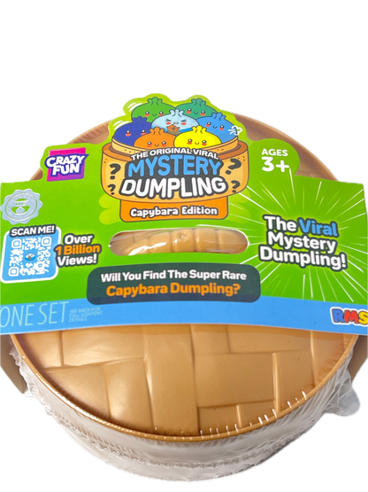 A Capybara Edition 'The Viral Mystery Dumping!' toy set in its retail packaging, featuring a brown woven basket-like container wrapped in clear plastic with a colorful green, blue, and orange cardboard insert.