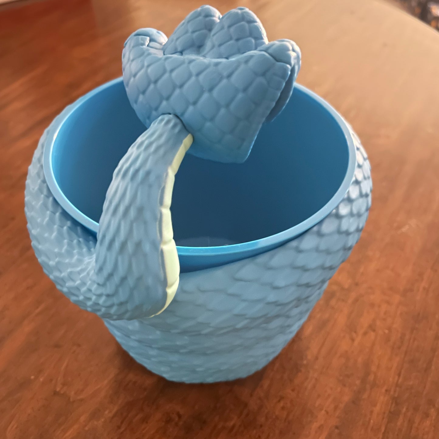 Blue textured cup with a matching dragon-shaped handle on a wooden surface