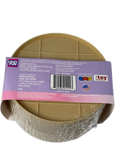 A round plastic toy bowl in a tan/beige color, wrapped in clear plastic and covered with a purple and pink product label. The label shows the brand 'Crazy Port' and various certification logos.