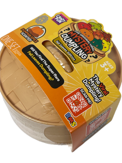 A packaged toy product labeled 'The Original Viral Mystery Dumpling! Fall Licensed Edition' by Crazy Fun, shown in its retail sleeve with a clear plastic-wrapped round dumpling visible inside. The packaging is predominantly yellow and orange with cartoon graphics and text including 'Pumpkin Spice Scared!' and 'Ages 3+'.