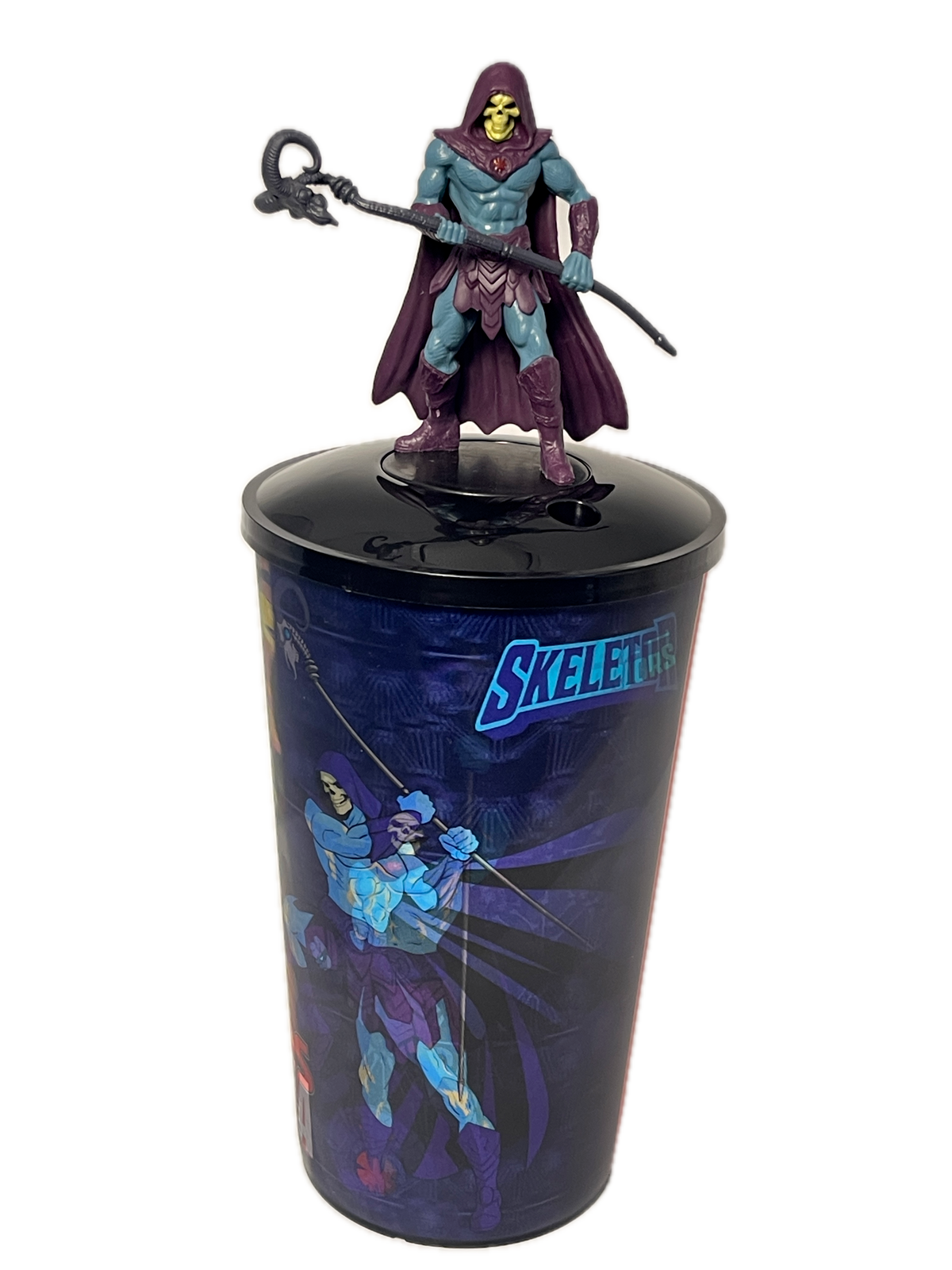 A Skeletor action figure emerging from a printed display cup featuring blue and purple comic-style artwork and the word 'SKELETOR' on a white background.