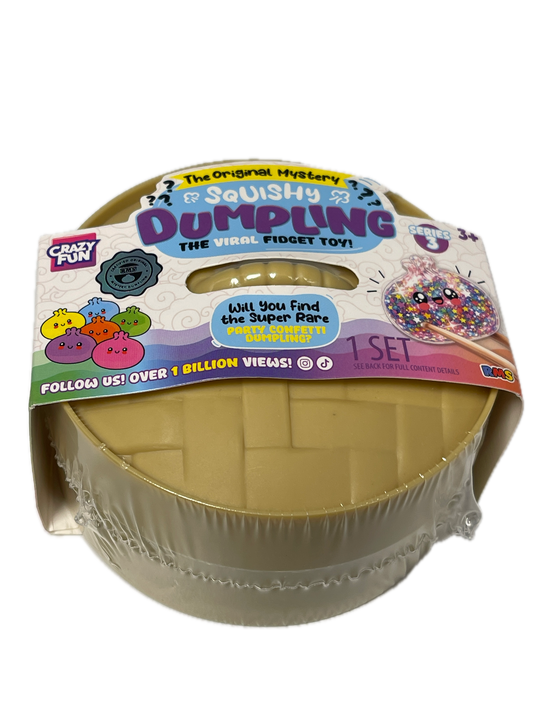 A packaged 'Dumpyling' squishy toy from Crafty Creations, shown in its clear plastic wrap with a colorful cardboard header card. The product is a round, beige-colored squishy with a grid pattern, and the packaging features various colorful graphics and text.