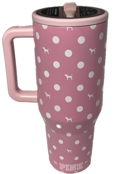 A pink insulated travel tumbler with a white polka dot pattern and small dog silhouette motifs, featuring a matching pink handle and the word 'PINK' printed on the side.
