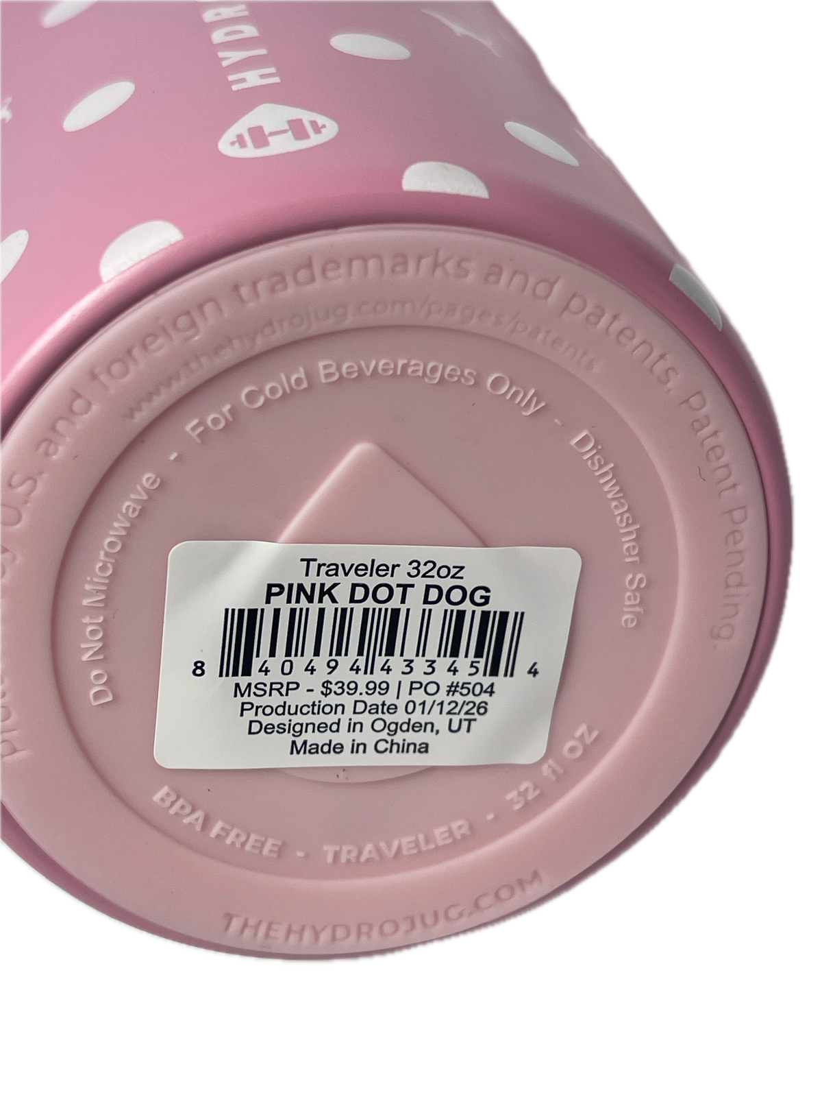 Close-up of the bottom of a pink polka-dot travel tumbler showing a white barcode label that reads 'Traveler 32oz PINK DOT DOG'.
