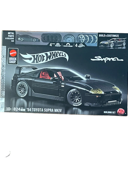 Hot Wheels Brick Shop '94 Toyota Supra MK IV building set box on a wooden floor, showing a black sports car model with red interior and toy parts icons at the top.