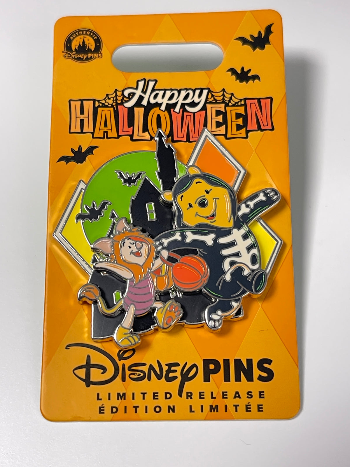 A Disney Pins Happy Halloween limited edition enamel pin on its original orange backing card. The pin features Winnie the Pooh and Tigger dressed in Halloween costumes, with a witch's hat, bats, and a haunted house in the background.