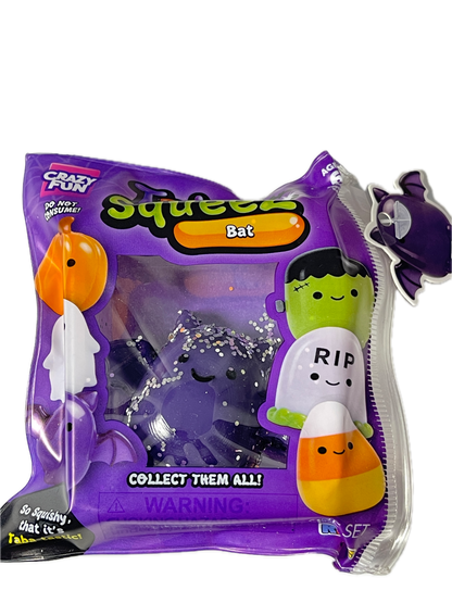 Packaged Squeezies Bat squishy toy in a purple bag with character graphics including Frankenstein, a corn cob, and a ghost, on a white background.