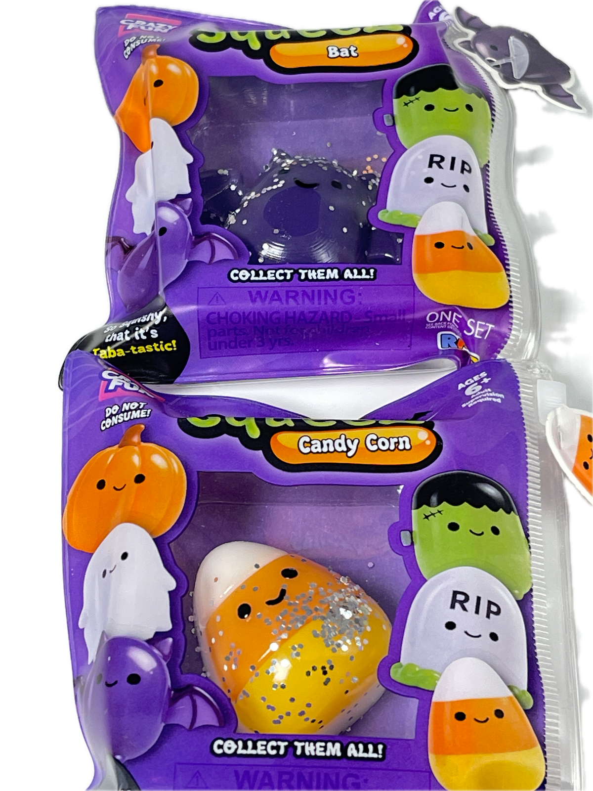 Two packaged collectible squishy toys in clear plastic bags with purple Halloween-themed packaging. One bag contains a dark purple ghost squishy, and the other contains a candy corn squishy with orange, white, and silver glitter details.