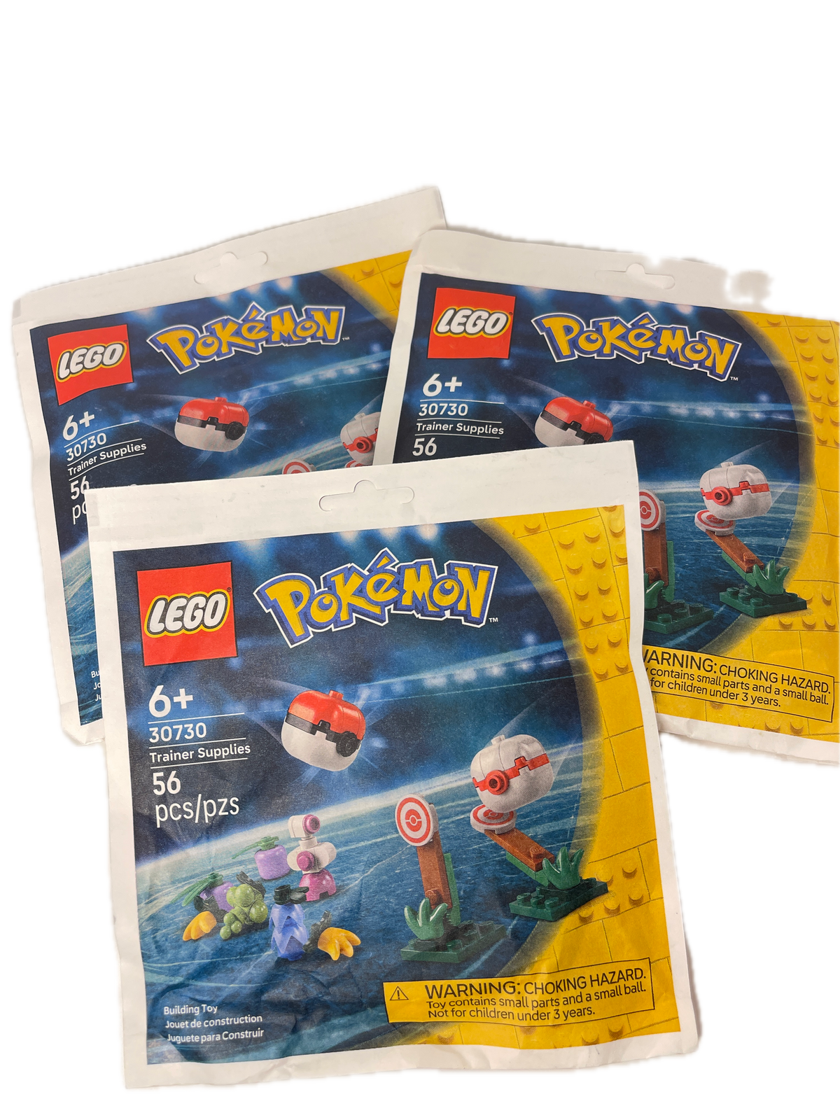 Three LEGO Pokémon blind bag packs fanned out on a white background, showing the yellow and blue packaging with LEGO and Pokémon branding.