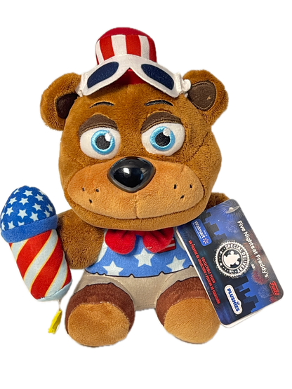 A plush teddy bear toy with a patriotic American flag theme, featuring a red, white, and blue star-spangled body, a matching star-spangled hat, and a blue hangtag that reads 'Five Biggest Freddy's' and 'PUSHINS'.