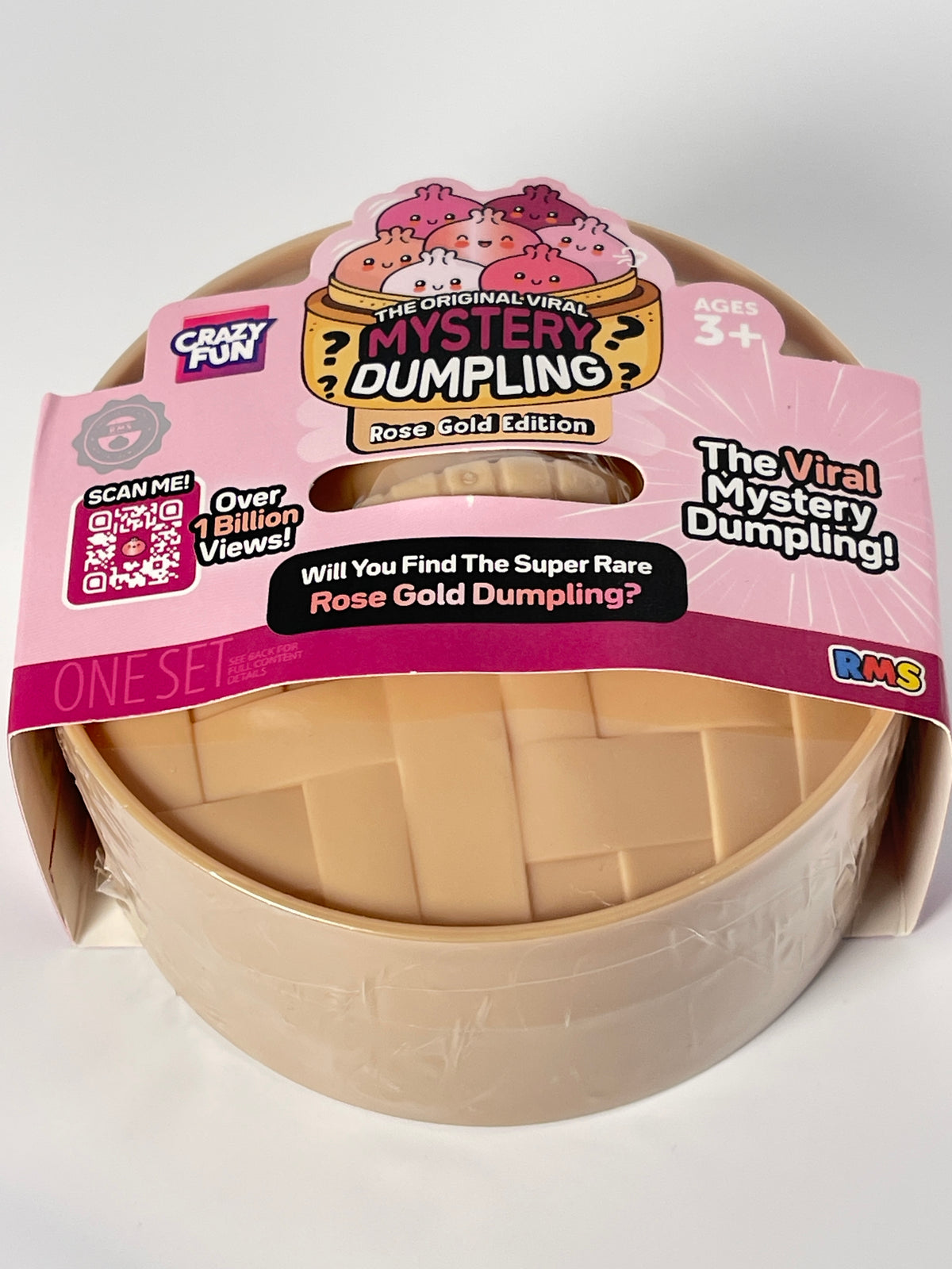 A packaged toy product labeled 'The Original Viral Mystery Dumpling Rose Gold Edition' on a plain light background. The item appears to be a round beige plastic dumpling-shaped toy inside a clear plastic sleeve with a pink retail hanger/card attached.