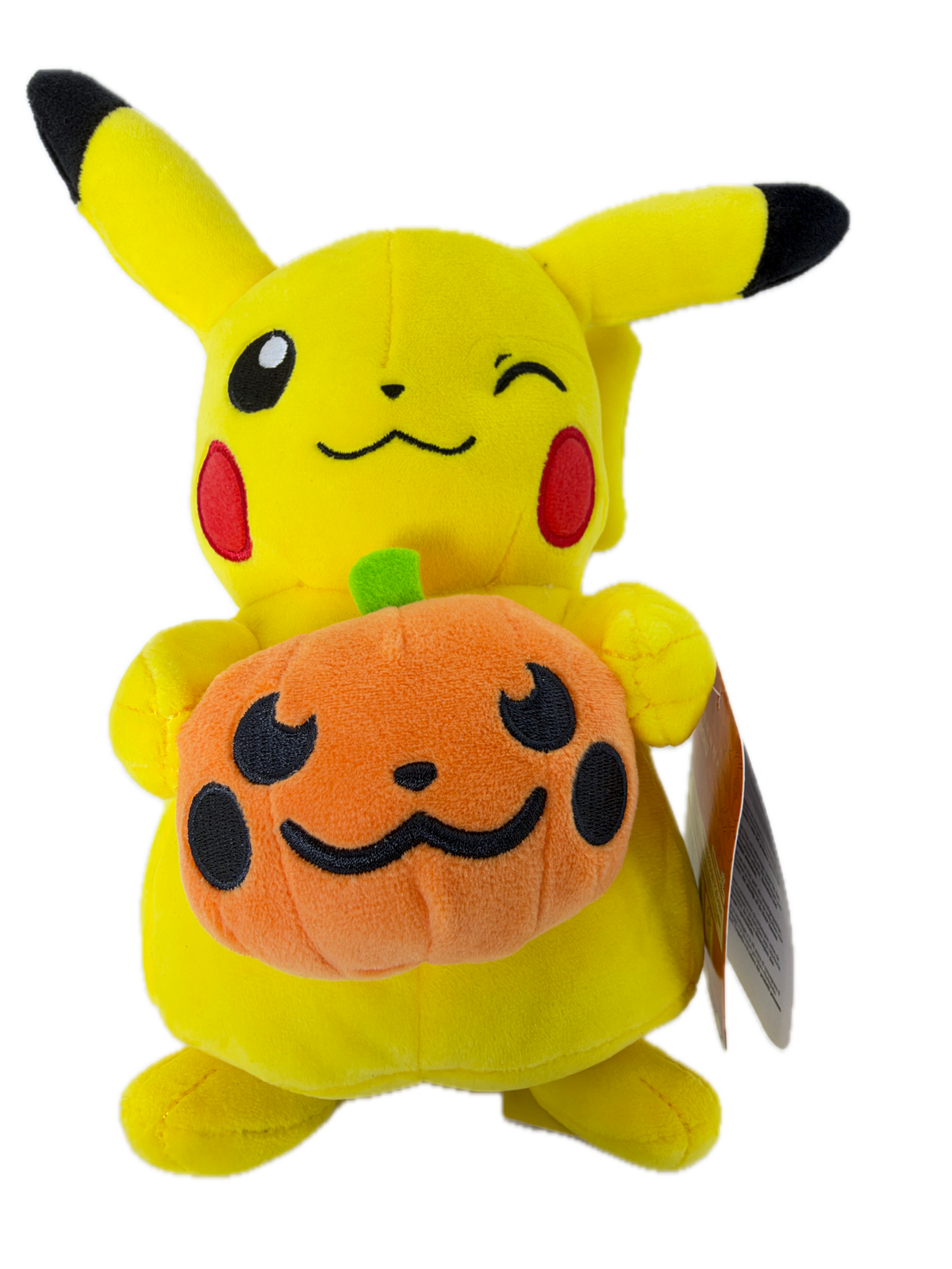 A yellow Pikachu plush toy lying down and holding an orange pumpkin with a black stitched face. The plush has black-tipped ears and tail tip, red cheeks, and a hangtag attached near the top right.