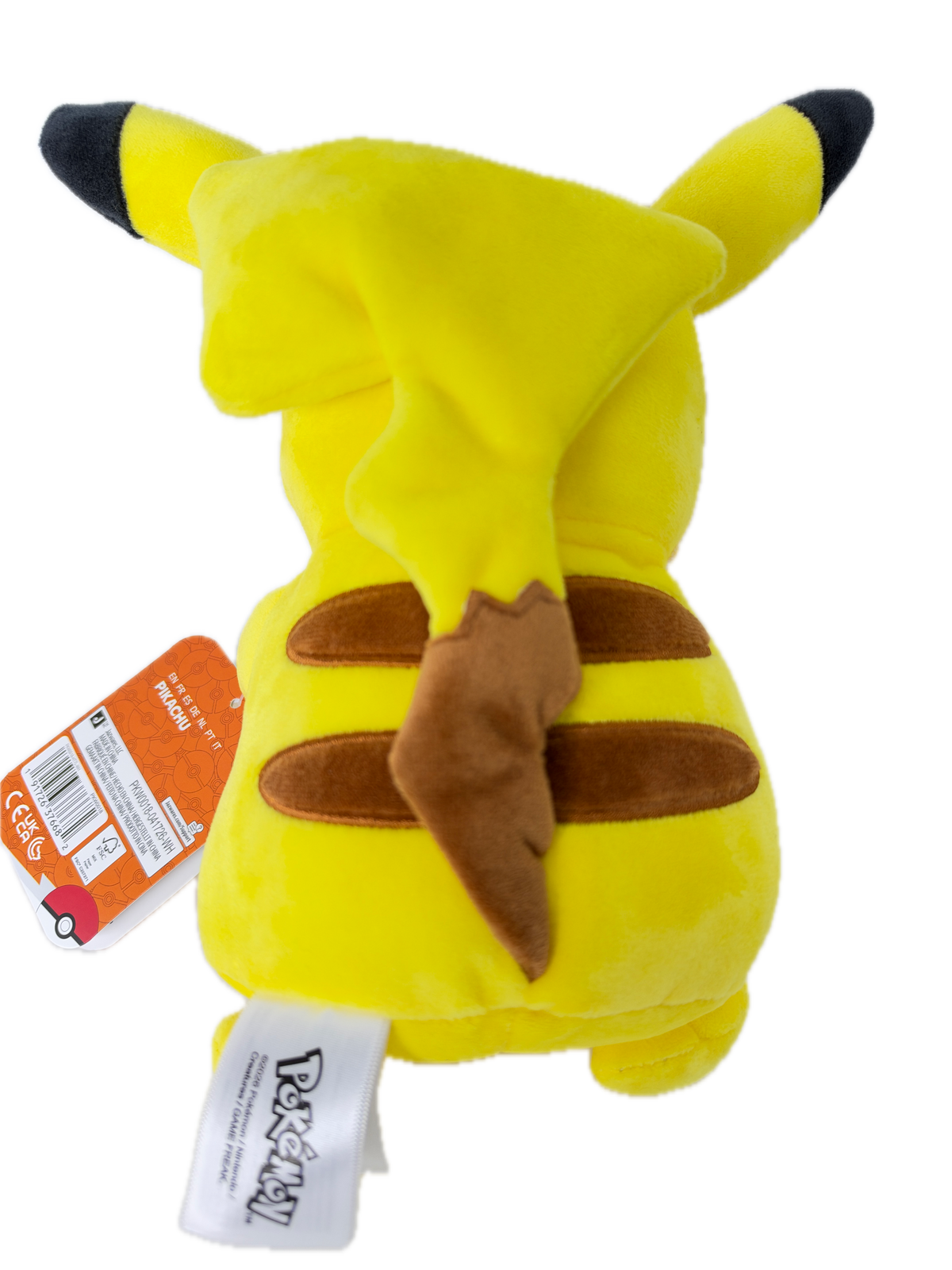 A yellow Pikachu plush toy with black-tipped ears and tail, brown ear patches, and a brown lightning-bolt detail on its back, shown on a white background with an orange retail hangtag and a white Pokémon brand tag.