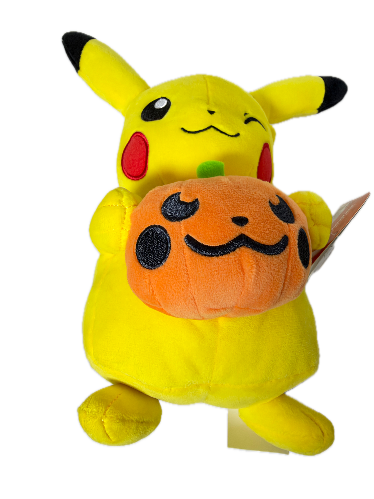 A yellow Pikachu plush toy lying on its side with an orange pumpkin face stuffed inside its mouth, shown against a plain white background.