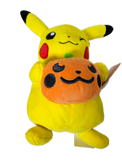 A yellow Pikachu plush toy lying on its side with an orange pumpkin face stuffed inside its mouth, shown against a plain white background.