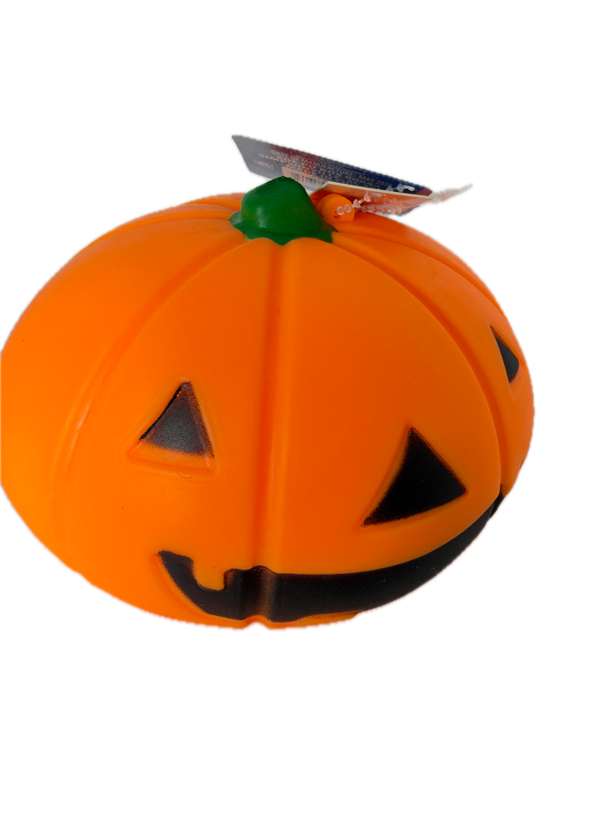 An orange squishy ack-o'-lantern toy with black carved facial features and a small green stem, shown on a plain white background with a hangtag attached.