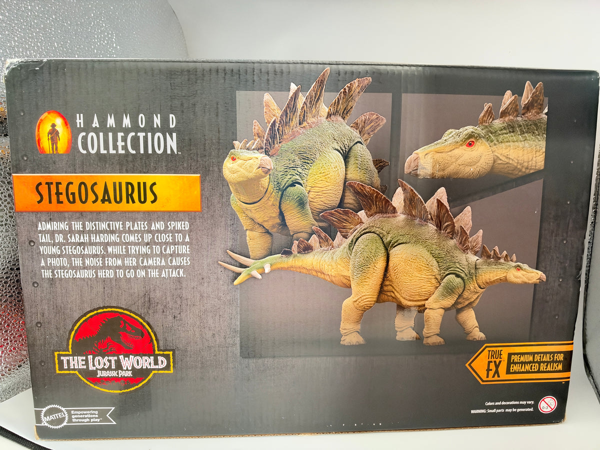 Hammond Collection Stegosaurus toy packaging from The Lost World Jurassic Park, featuring a dark gray box with images of the green and tan dinosaur and Jurassic Park branding.