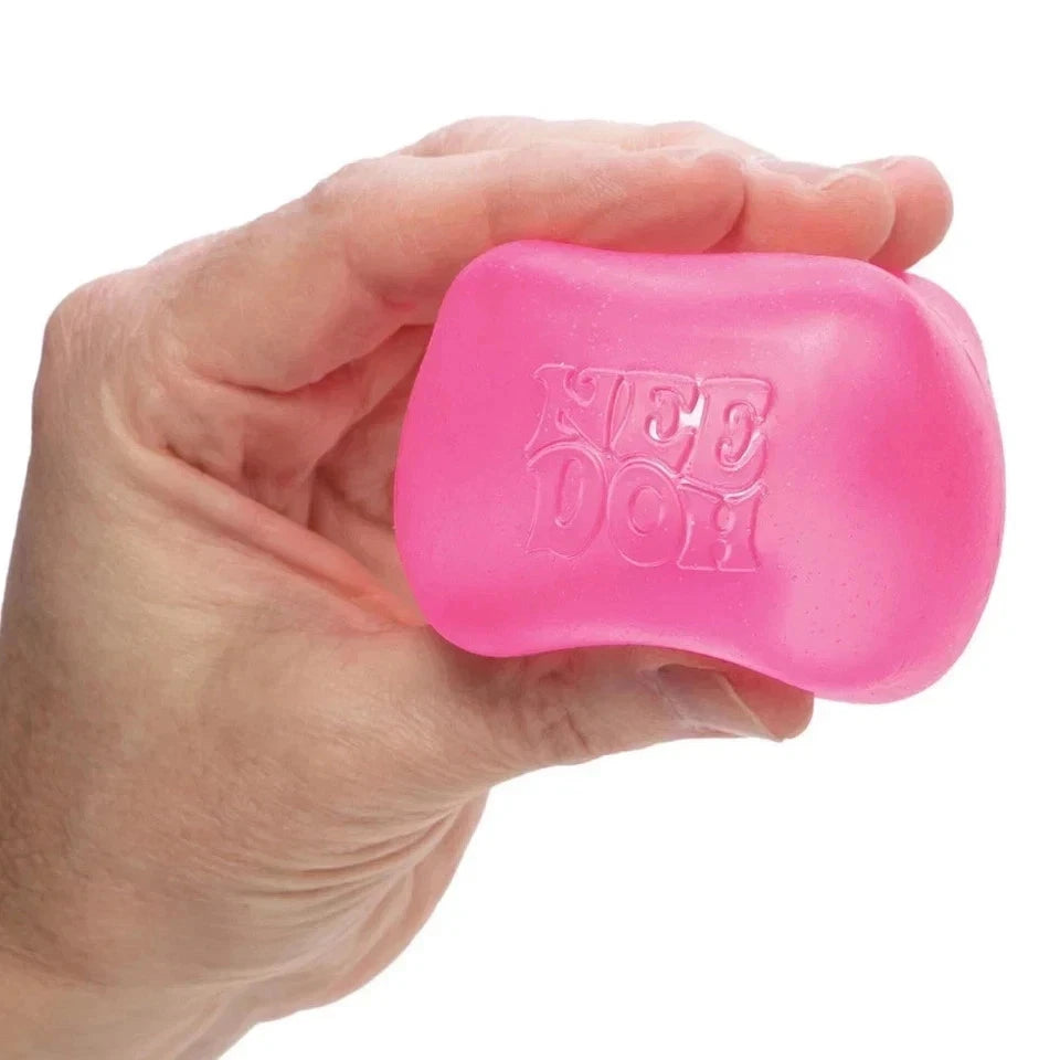 Pink dog toy with 'Nee Doh' branding held in a hand against a white background