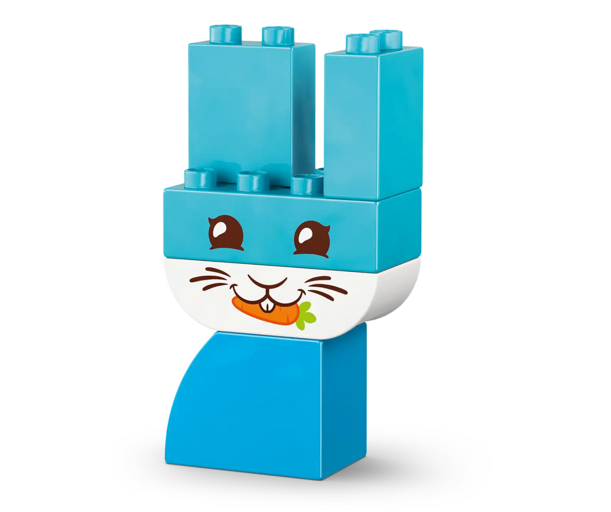 A toy building block figure shaped like a rabbit head and neck, made from bright blue and white blocks with printed facial features including brown eyes, white whiskers, and an orange carrot.