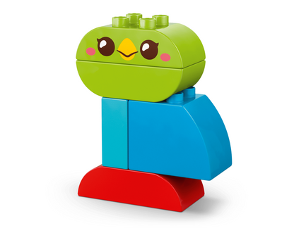 A colorful toy building block figure resembling a cute bird or duck, with a green head featuring a smiling face, blue body pieces, and a red base, shown on a clean white background.