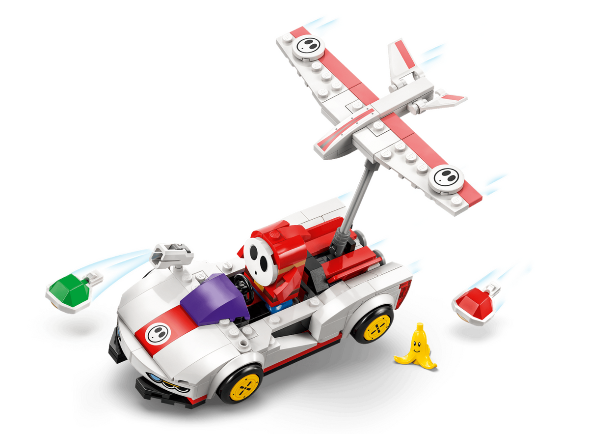 A LEGO-style toy race car with a red and white striped canopy, yellow wheels, and a small airplane mounted above it, shown on a clean white background with small accessory pieces nearby.