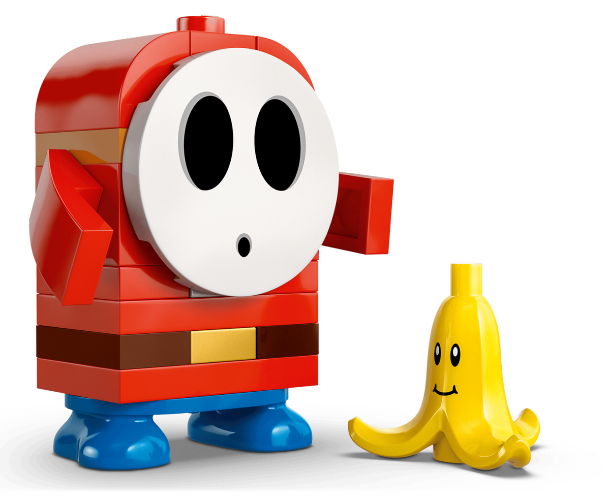 A LEGO-style toy figure resembling a red ghost with a white face and blue feet, standing next to a small yellow banana-shaped figure on a clean white background.