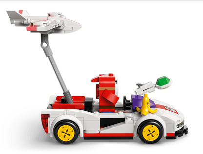 A LEGO-style toy supercar in white, red, and black with yellow wheels, shown from the side on a light gray background. It features a raised gray arm holding a small white and red airplane, a purple side panel, a yellow banana-shaped figure, and a green-tinted front light.
