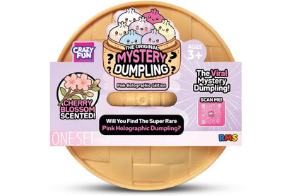 Crazy Fun The Original Mystery Dumpling Pink Holographic Edition, featuring a round wooden basket containing a pink holographic dumpling and a decorative product card with illustrations of cherry blossoms and a pink QR code.