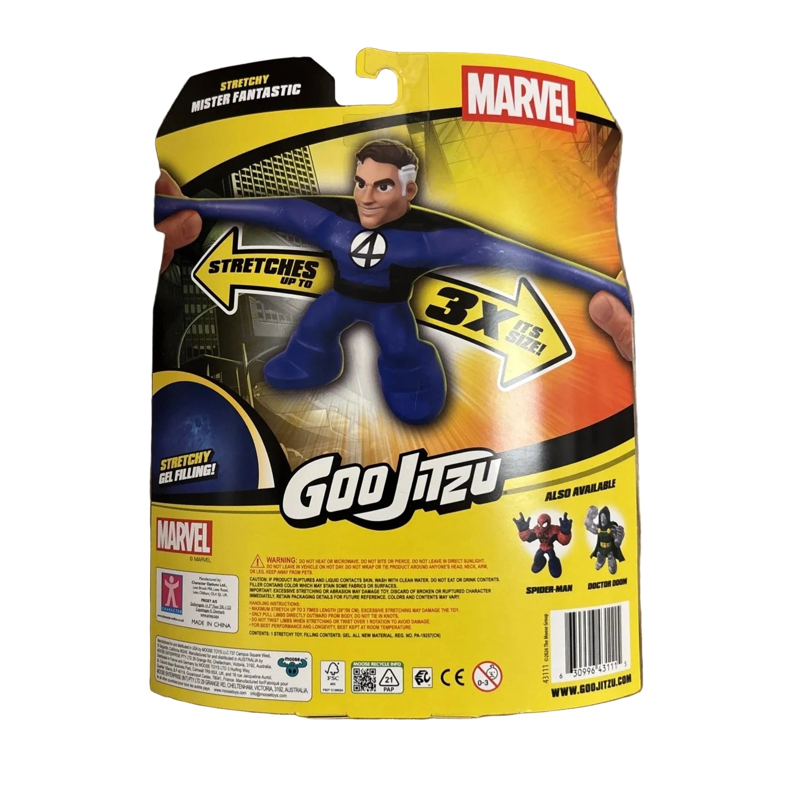 Goo Jitsu Marvel Mister Fantastic action figure in its original retail blister packaging, displayed on a light brown wood floor. The packaging is predominantly yellow and black with a graphic of the blue-suited figure stretching.
